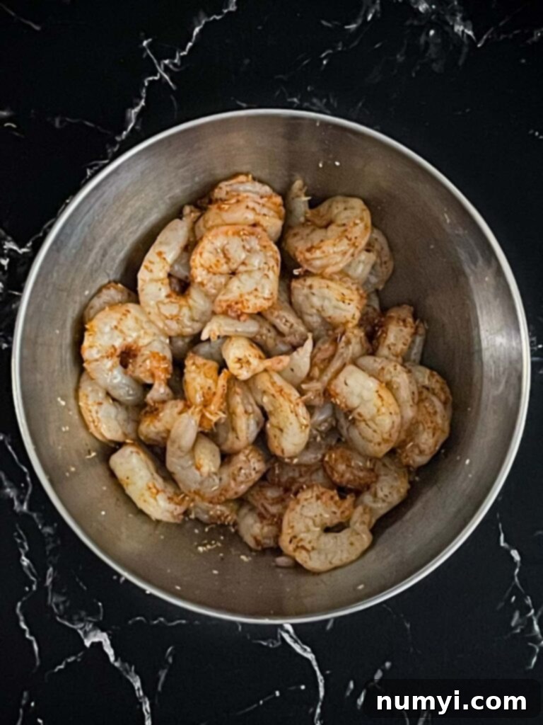 Fresh Grilled Shrimp and Corn Salad 6 Raw shrimp seasoned with spices in a white bowl.