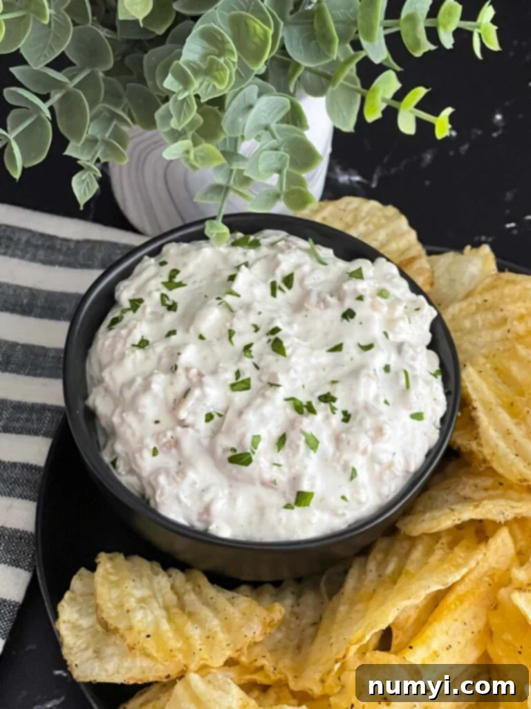 Creamy Clam Dip 2 Clam dip in a dark bowl surrounded by kettle potato chips.