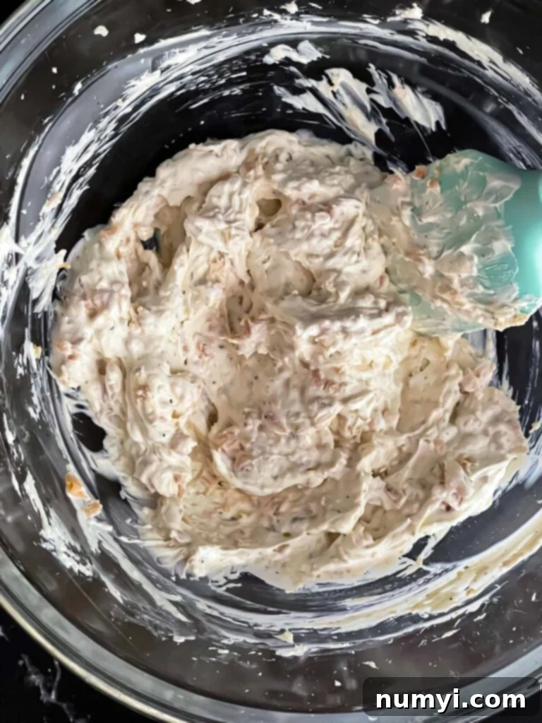 Clam dip recipe ingredients mixed together in a glass mixing bowl.