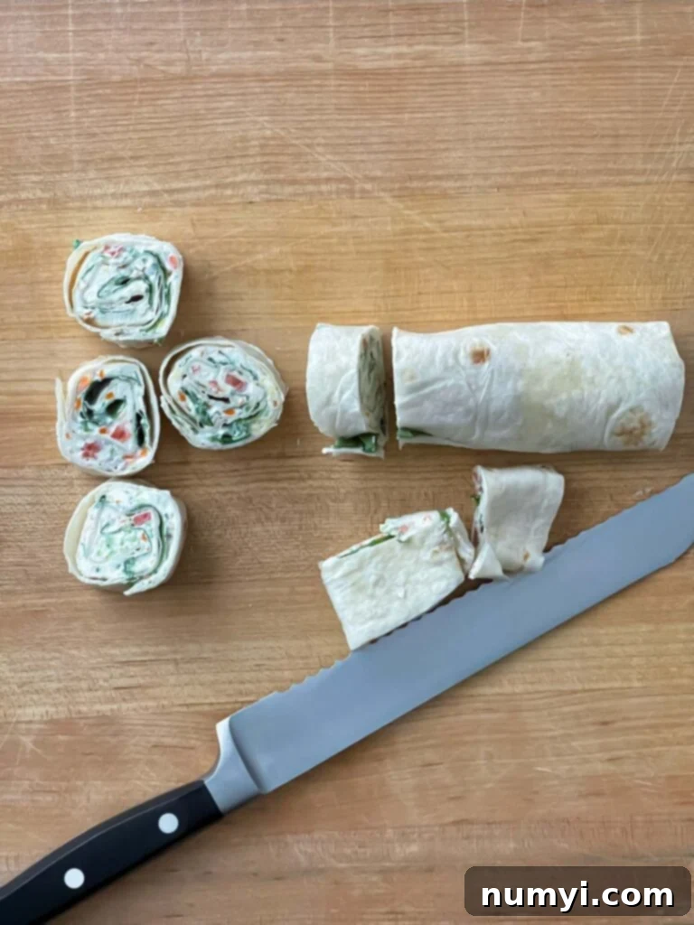 Veggie Tortilla Pinwheels 9 Sliced veggie tortilla roll ups on a wooden cutting board.