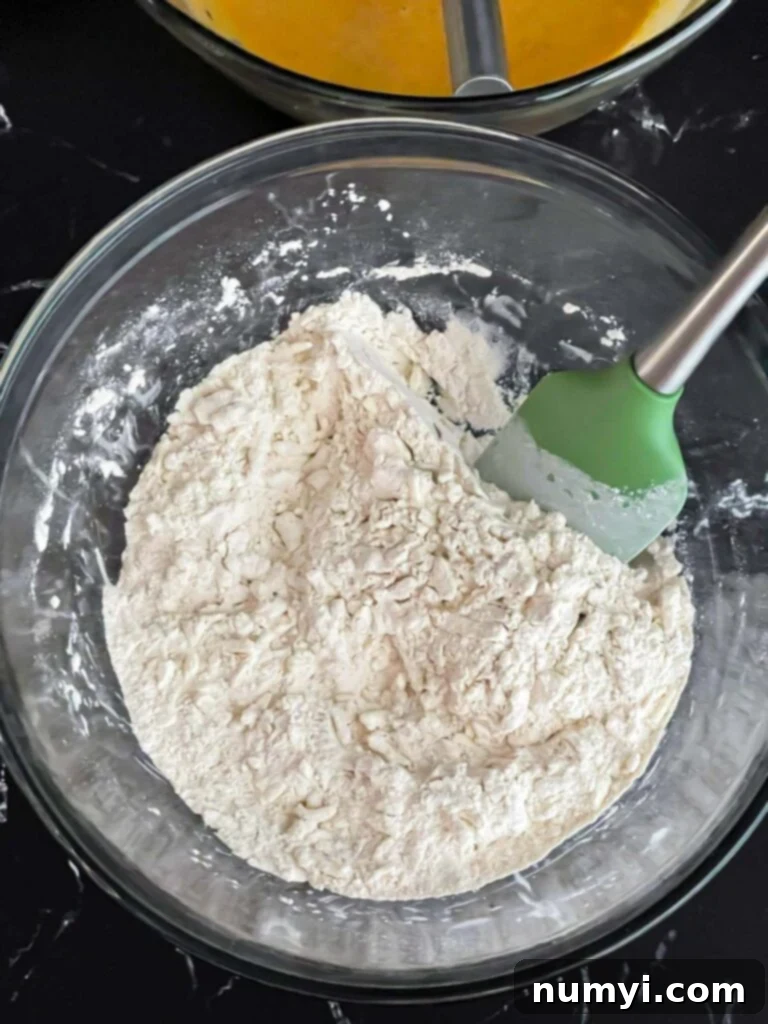 Shredded frozen butter added to the dry ingredients in a glass mixing bowl.