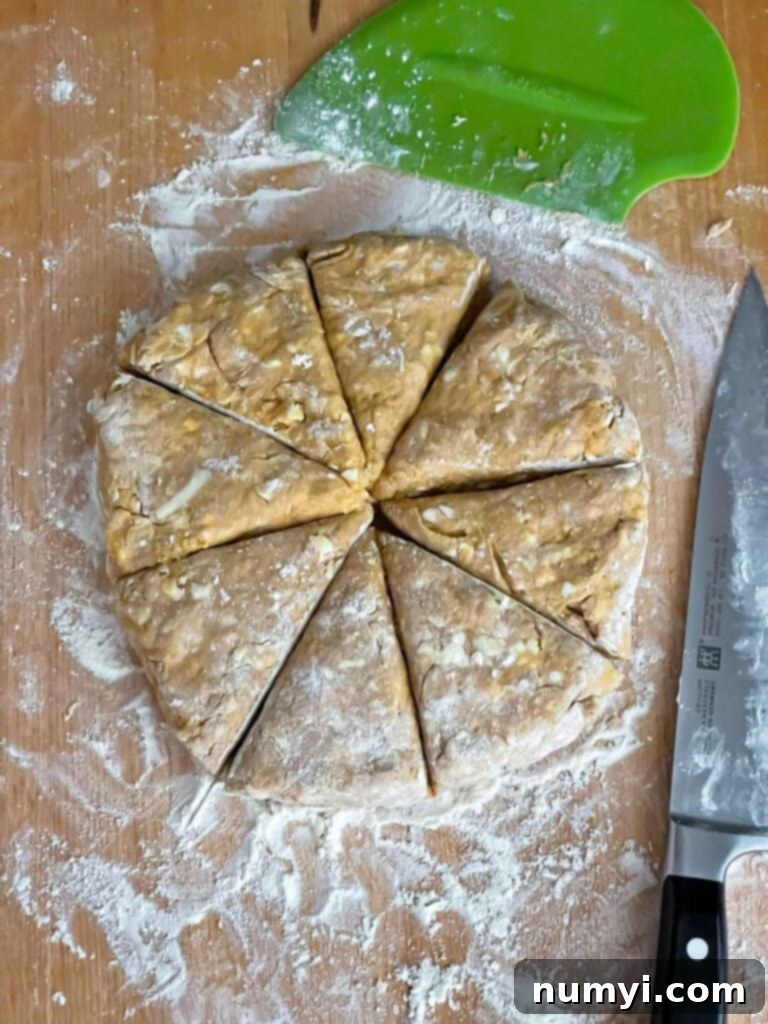 Pumpkin scone dough cut into eight equal pieces on a wooden board.