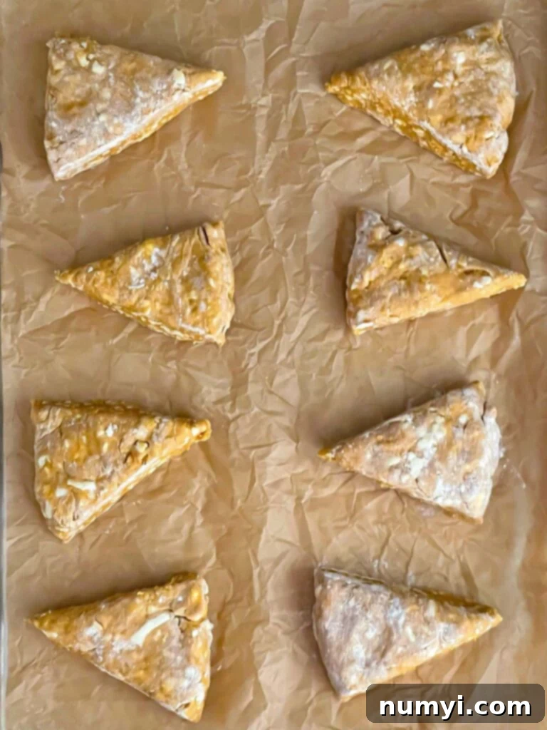 Unbaked pumpkin scones on a parchment paper lined baking sheet.