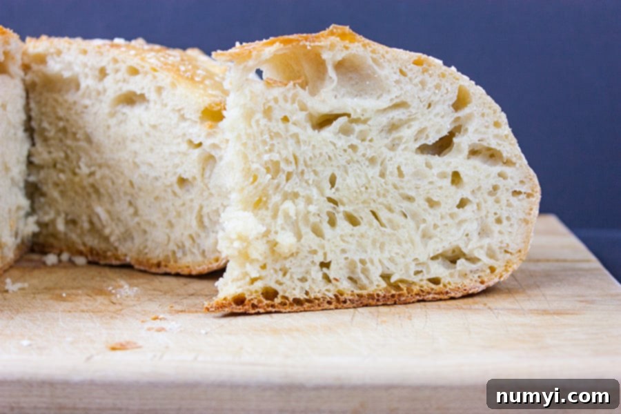 Golden brown No-Knead Large Dutch Oven Bread cooling on a wooden cutting board, showcasing its rustic crust and inviting texture.