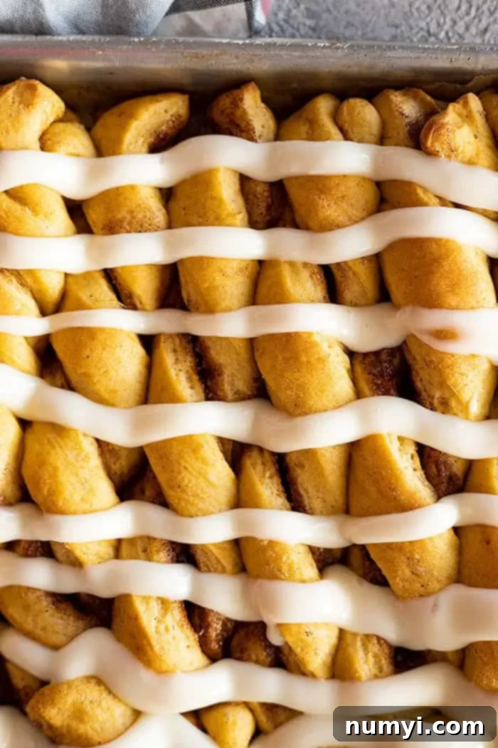 Overhead view of a tray of warm pumpkin twists, generously drizzled with creamy white cream cheese frosting.
