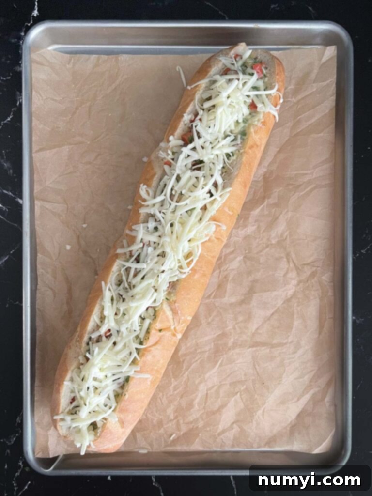 Loaded Sausage and Egg Baguette 13 Stuffed French bread loaf topped with cheese, ready for baking.