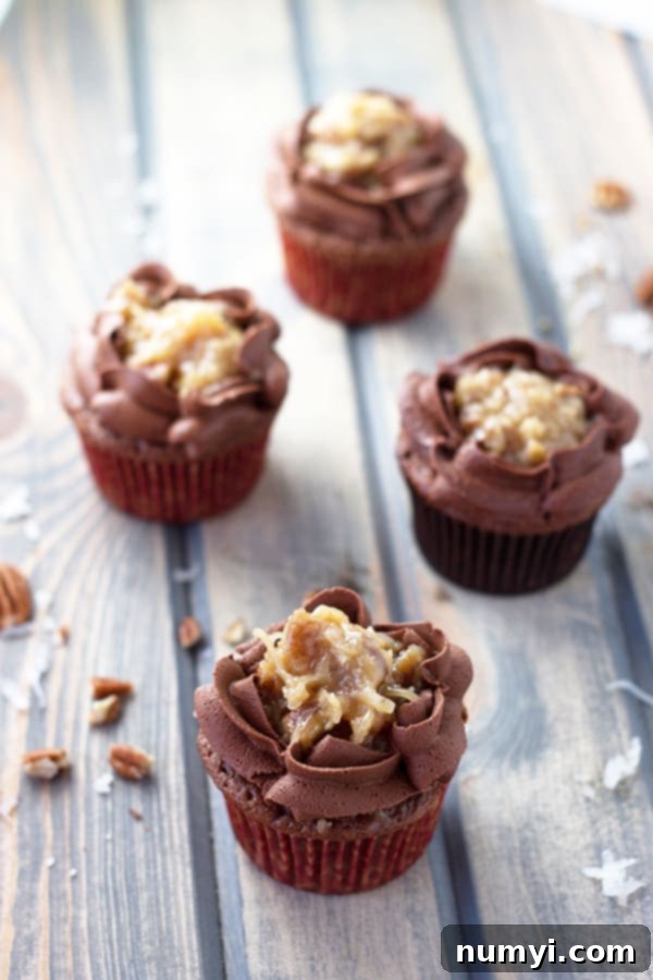 German Chocolate Cupcakes 2 Four German chocolate cupcakes topped with chocolate and coconut caramel pecan frosting, showcasing their delicious layers.
