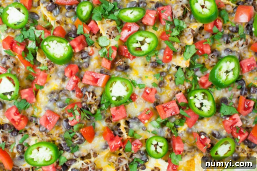 Crispy Sheet Pan Beef Nachos loaded with cheese and toppings