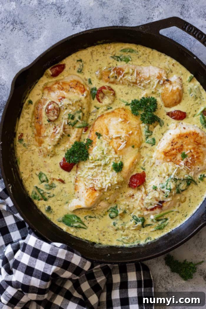 Skillet with creamy tuscan chicken garnished with fresh parsley.