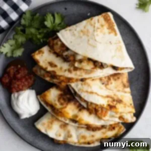 Overhead view of crispy black bean sweet potato quesadillas on a dark plate with sour cream and salsa off to the side, showcasing the delicious meal.