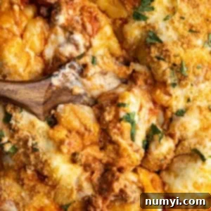 Overhead view of baked gnocchi with a spoon in the middle showing how gooey the casserole is.
