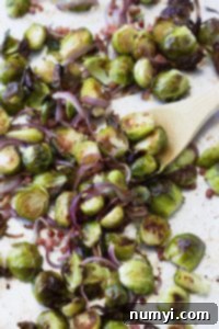 Oven-Roasted Brussels Sprouts with Ham & Caramelized Onions 5 A close-up shot of perfectly roasted Brussels sprouts on a white plate, showcasing their golden-brown edges and tender texture.