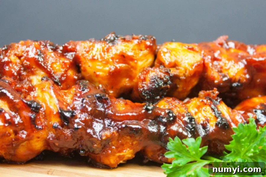 Perfectly grilled Bacon Paste BBQ Chicken Kebabs arranged on a rustic wooden cutting board, showcasing their rich, caramelized exterior and the subtle char marks from the grill.