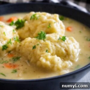 Close up of a bowl of creamy turkey and dumpling soup. Garnished with a little chopped parsley and black pepper.