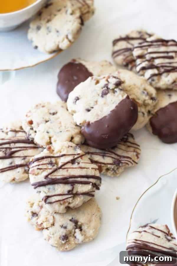 Close-up shot of pecan shortbread cookies with melted mini chocolate chips, some drizzled with extra chocolate, showcasing their irresistible texture.
