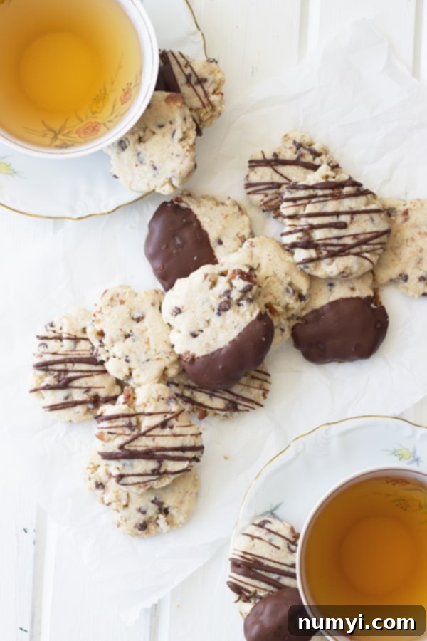 An inviting overhead view of two cups of tea flanking a generous pile of chocolate chip pecan shortbread cookies, ready for a cozy moment.