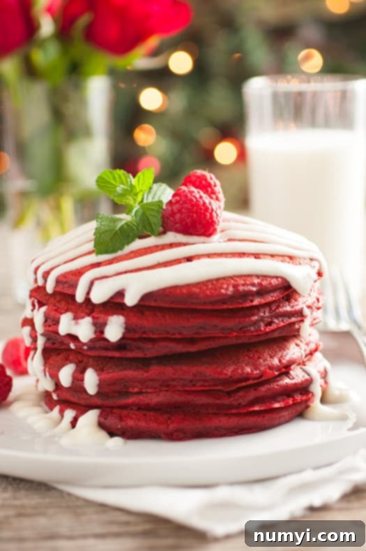 Vibrant Red Velvet Pancakes with rich Cream Cheese Glaze, a decadent Christmas morning treat.