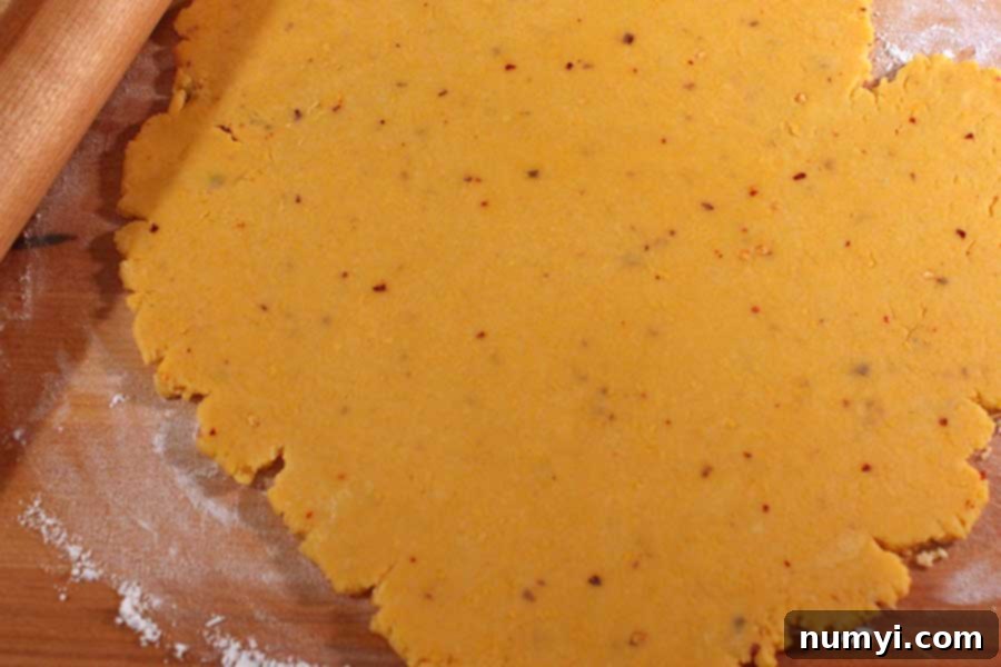 Whip Up Your Own Spicy Cheese Crackers 5 Spicy Cheese Cracker dough rolled out thinly on a lightly floured wooden board, ready for cutting.