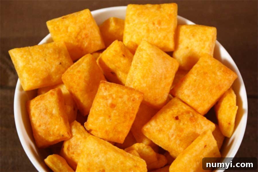 Whip Up Your Own Spicy Cheese Crackers 8 An inviting close-up of a white bowl overflowing with freshly baked spicy cheese crackers, perfectly golden and ready to be devoured.