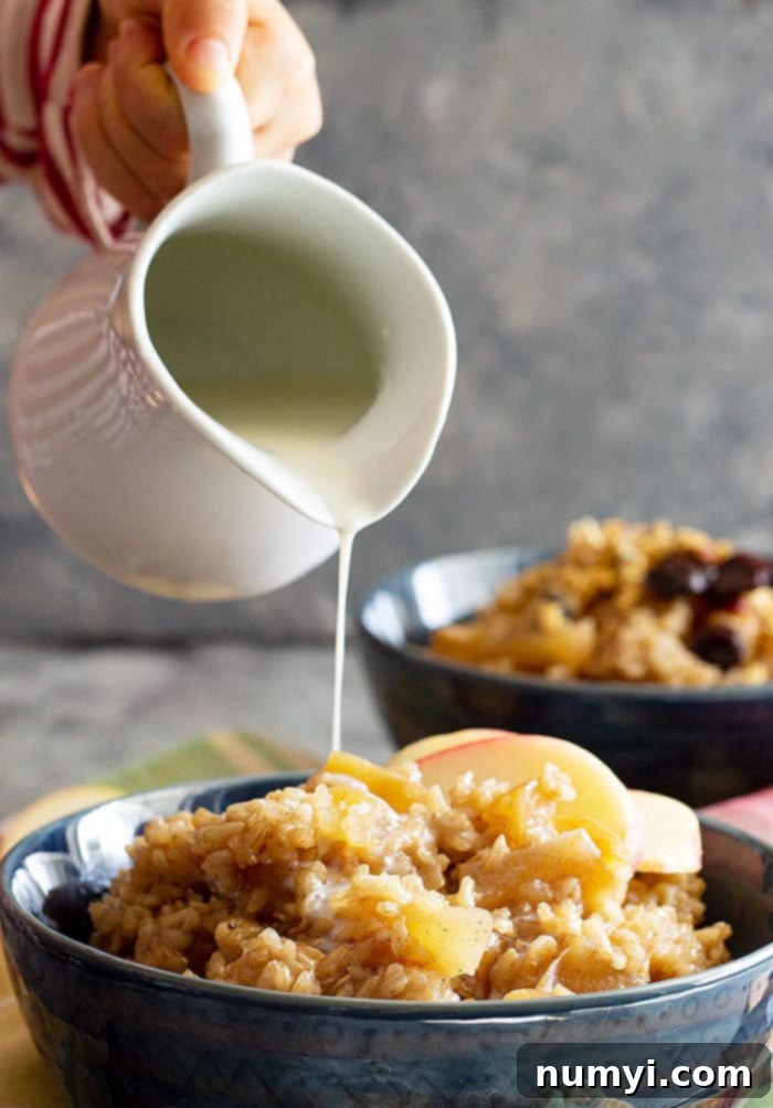 Creamy milk being poured over a bowl of Slow Cooker Cinnamon Apple Breakfast Rice, enhancing its richness.