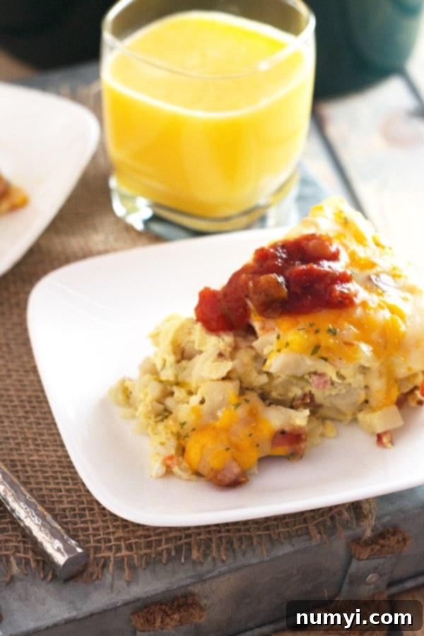 Overnight Slow Cooker Sausage and Potato Bake 4 A delectable serving of breakfast casserole, perfectly topped with vibrant salsa, resting beside a refreshing cup of orange juice, showcasing a complete and inviting breakfast.