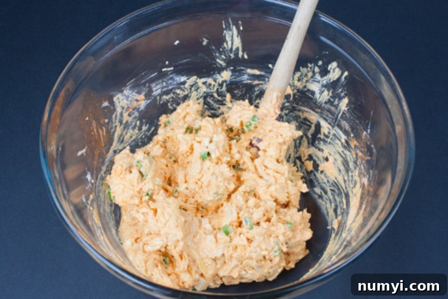 Buffalo Chicken Pinwheels ingredients mixed in a glass mixing bowl.