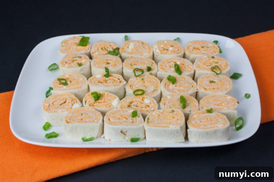 Buffalo Chicken Pinwheels on a platter garnished with diced green onions.