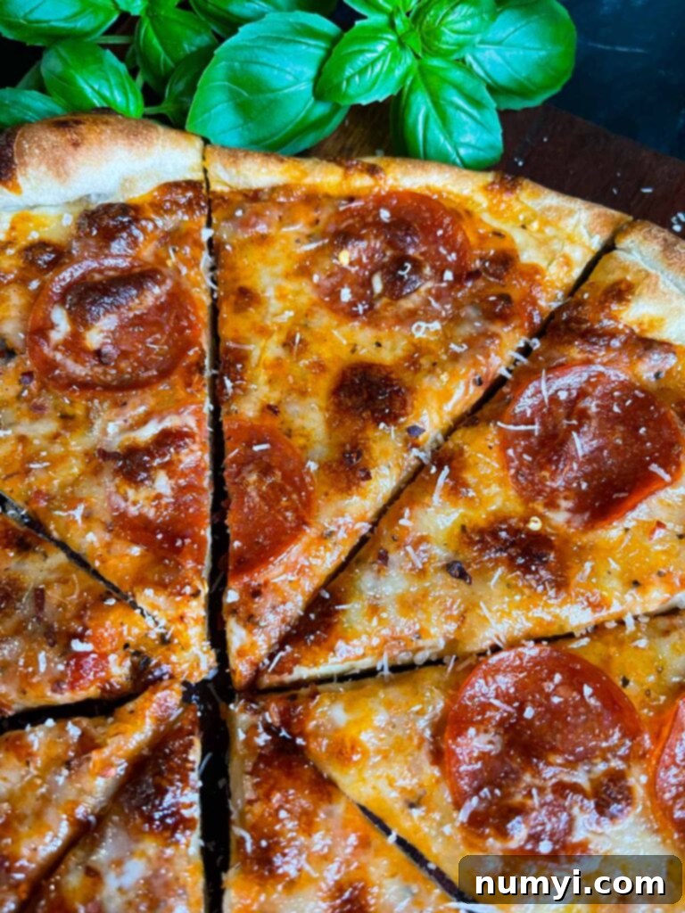 Homemade pepperoni pizza with Pecorino Romano and red pepper flakes, made with homemade pizza dough.