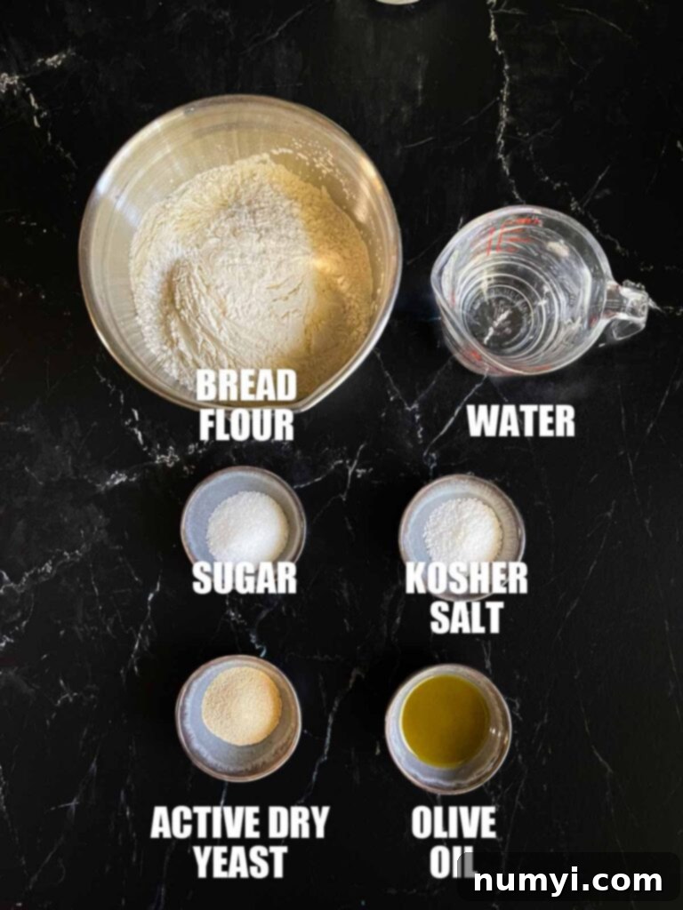 A flat lay of ingredients needed to make pizza dough: flour, yeast, sugar, salt, olive oil, and water.