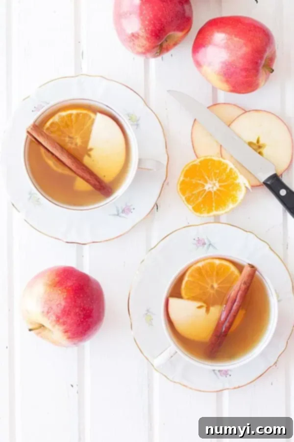 Slow Cooker Apple Cider 4 overhead: mulled apple cider from slow cooker in mugs with slices of oranges and apples, ready to be enjoyed
