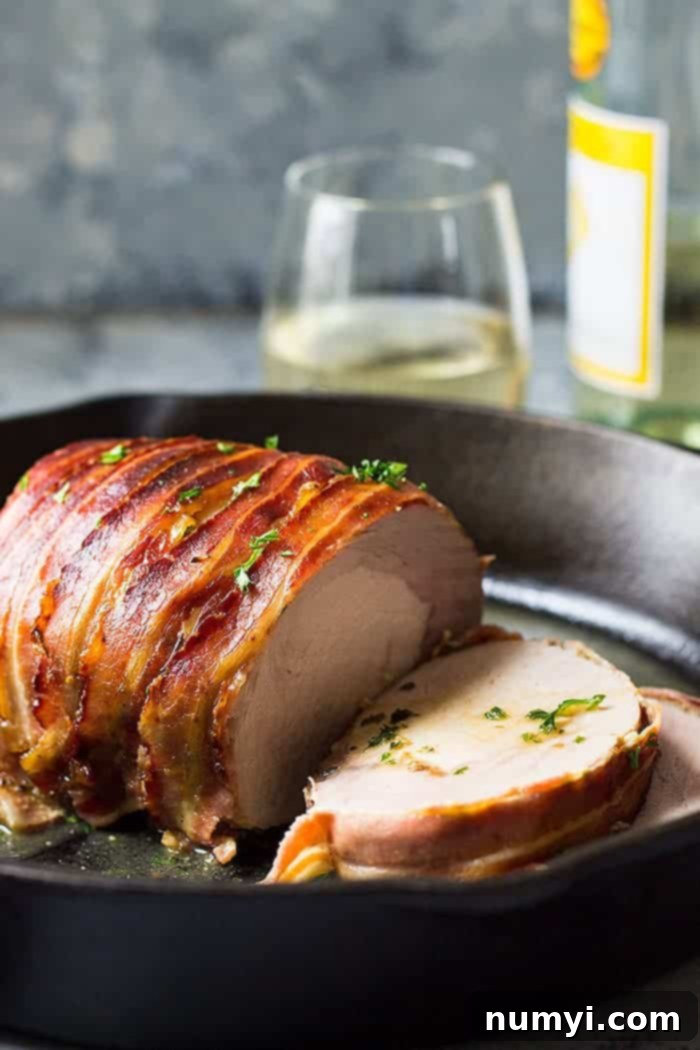 Crisp Bacon-Wrapped Pork Loin 4 Slices of bacon wrapped pork loin beautifully arranged in a cast iron skillet, with some fresh rosemary for garnish.