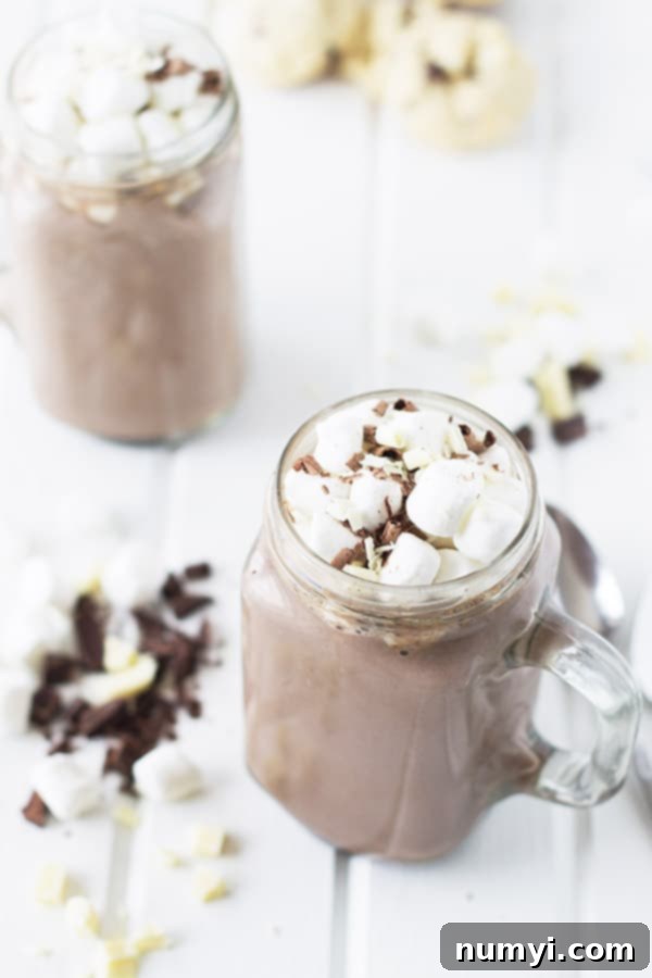 an overhead photo of a mason jar mug of slow cooker hot chocolate topped with marshmallows and chocolate bits