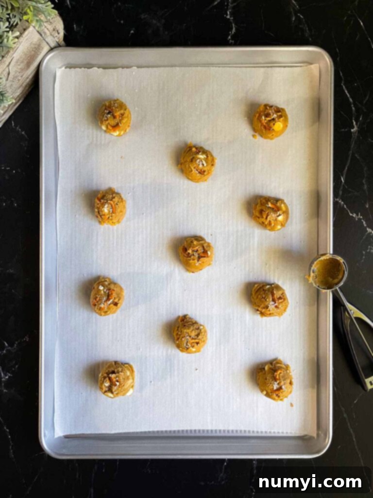 Salted Butterscotch Pretzel Cookie dough balls, perfectly scooped and sprinkled with sea salt, arranged on a parchment paper lined baking sheet.