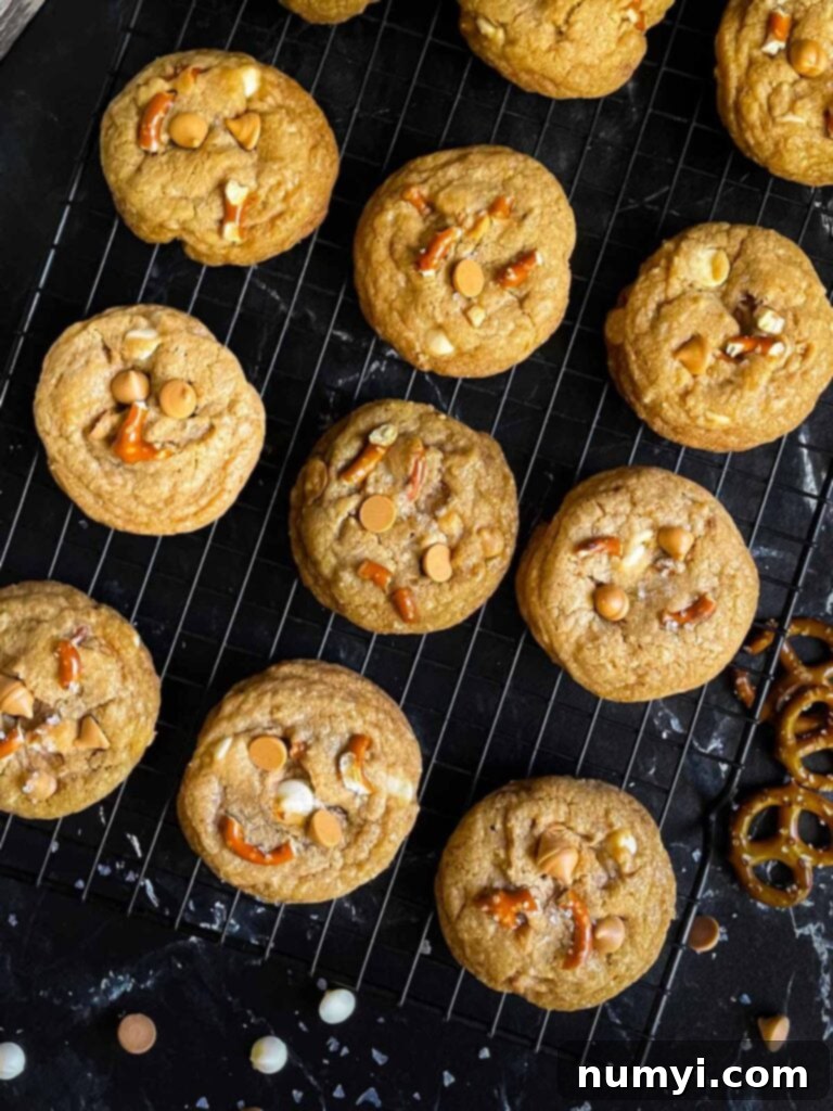 Freshly baked Salted Butterscotch Pretzel Cookies cooling on a wire rack on a dark surface.