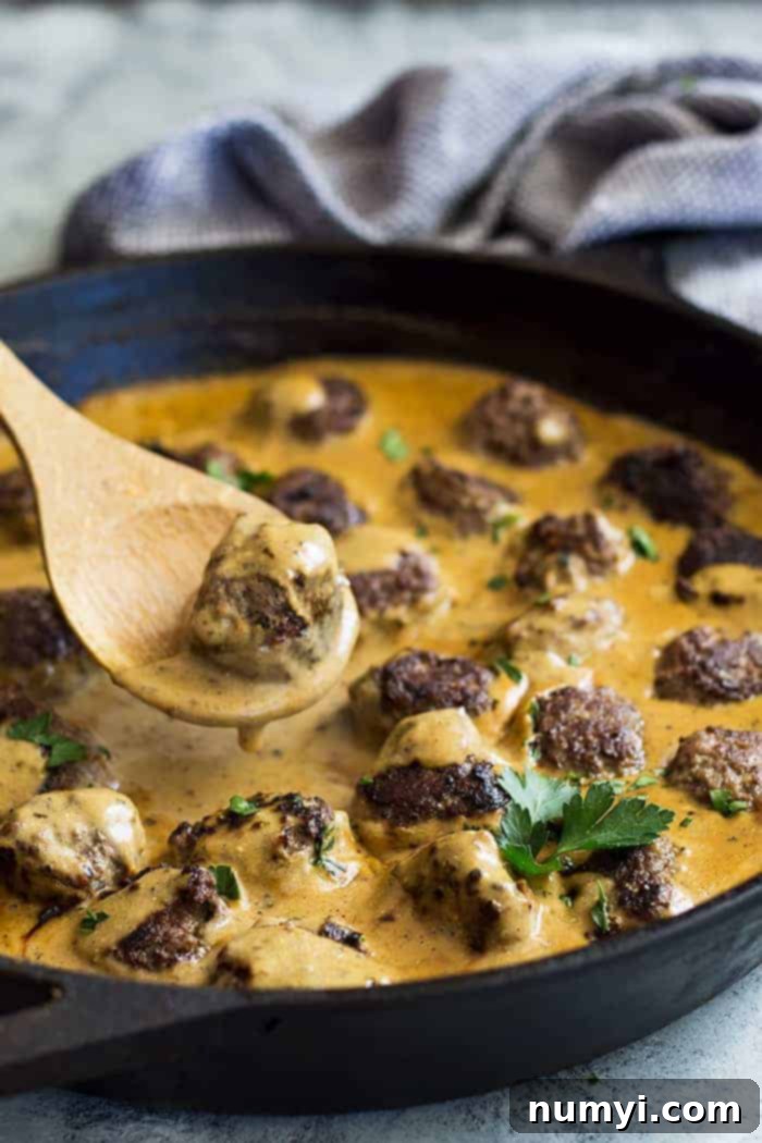 Pan of swedish meatballs with a spoon lifting one out. 