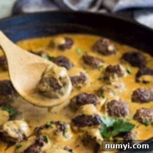 Pan of swedish meatballs with a spoon lifting one out.
