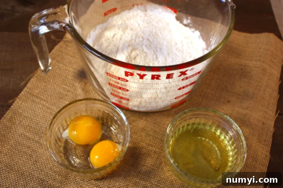 Essential pancake ingredients: flour in a clear glass bowl, separated egg yolks in one ramekin, and separated egg whites in another, ready for preparation.