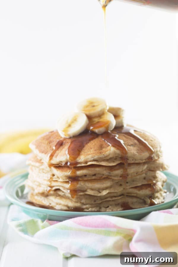 a stack of banana pancakes with slices on top and homemade caramel cinnamon syrup drizzled on top
