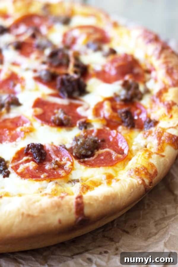 Close-up shot of an assembled deep dish pizza before baking, showcasing multiple types of cheese generously layered over three different meats.