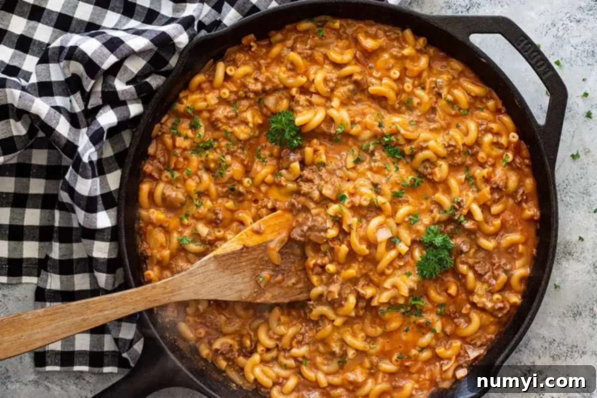 Overhead view of cast iron skillet with hamburger helper and a wooden spoon.