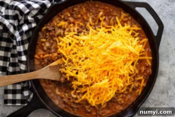 Overhead view of adding cheese to the skillet.