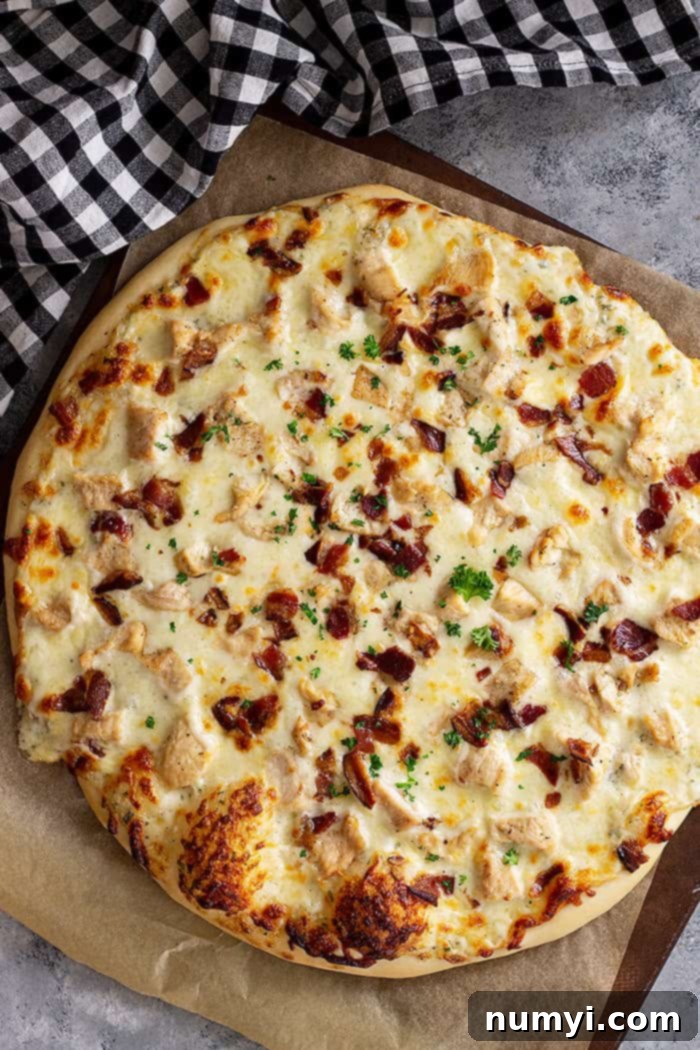 The Ranch Hand's Special 5 Top down view of a freshly baked Chicken Bacon Ranch Pizza, with a golden crust and bubbly, melted cheese, ready to be sliced.