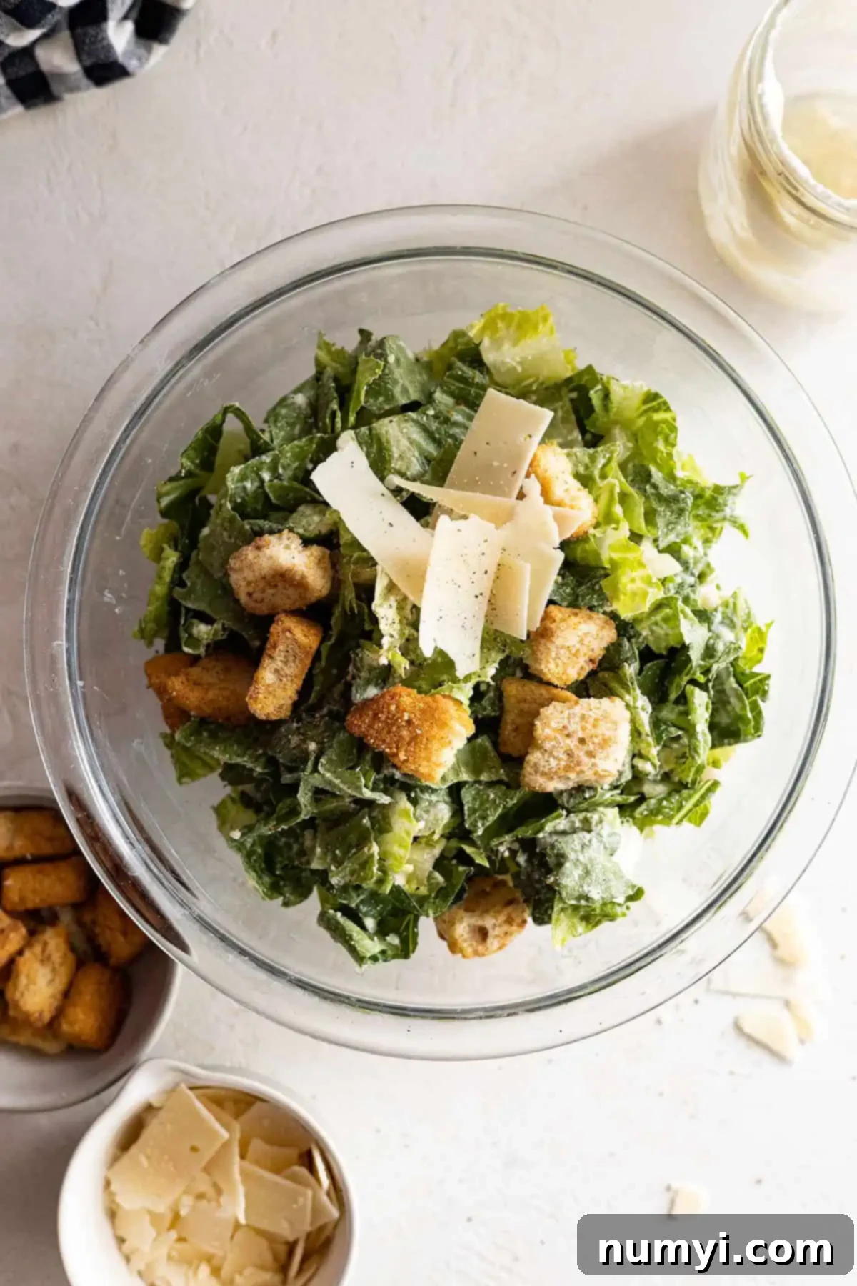 Overhead view of Caesar salad in a bowl dressed with dressing, parmesan, and croutons. 