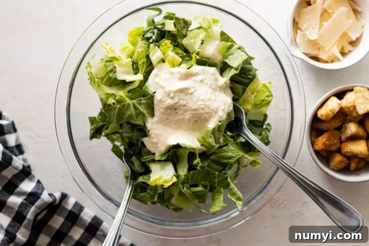 Overhead of salad being tossed in a bowl. Garnishes off to the side. 