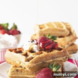 Titled image showing strawberry chocolate chip waffles with syrup and whipped cream