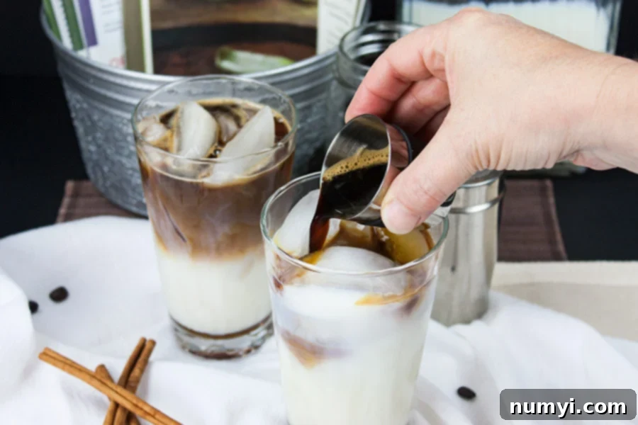 Frosted Cinnamon Macchiato 4 Iced Cinnamon Macchiato - espresso shots being poured over the milk in a clear glass