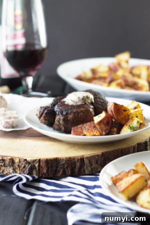 A beautifully set table featuring plates of perfectly cooked filet mignon, glistening with melted red wine compound butter, alongside golden roasted potatoes and a glass of deep red wine.