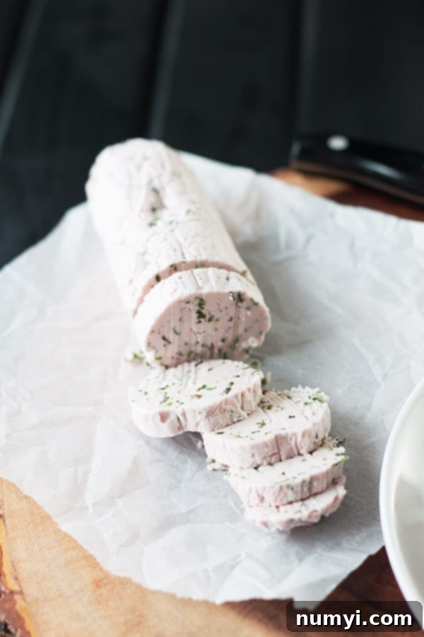 A perfectly rolled log of red wine compound butter, sliced into medallions, showcasing the vibrant herbs within.