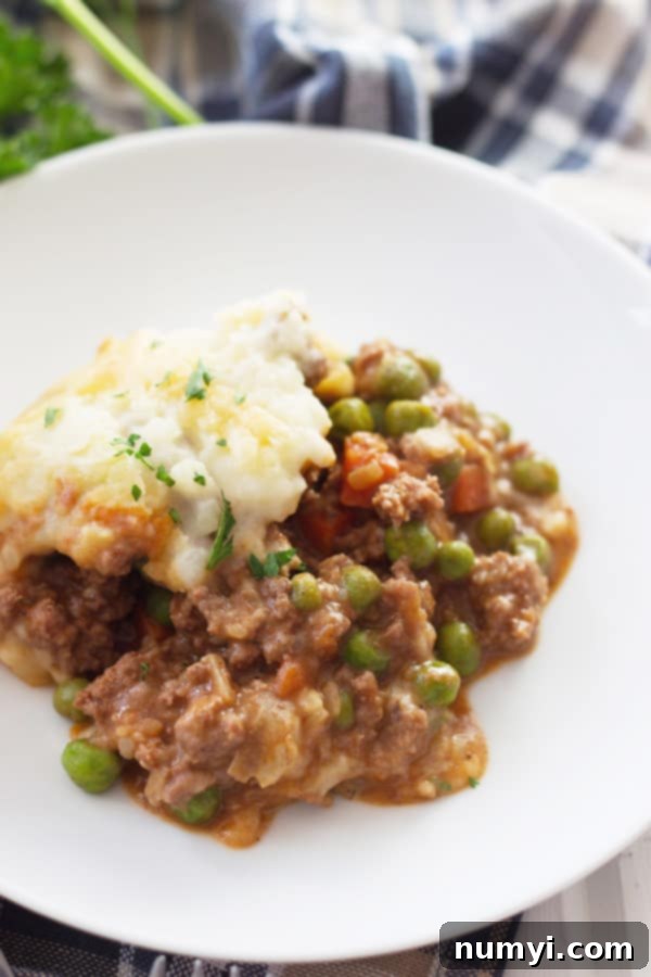 close up photo of shepherd's pie with ground beef, veggies, and mashed potatoes, showing a golden brown potato topping