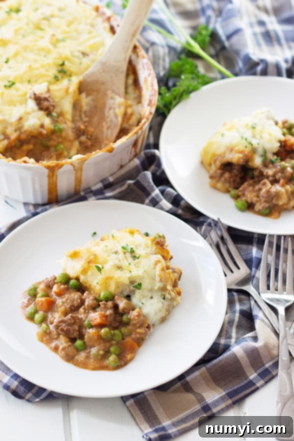 a casserole dish full of shepherd's pie and two plates with a serving on them, ready to eat